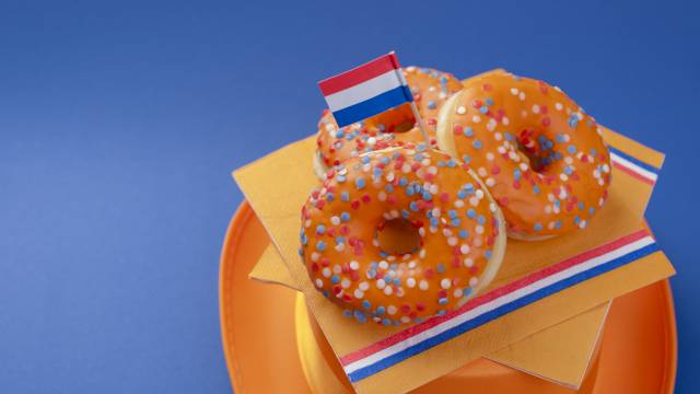 Orangefarbene Donuts mit Streuseln und niederländischer Flagge, serviert zur Feier des Königstages