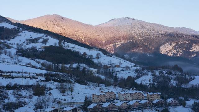 Verschneite Landschaft im Baskenland mit Bergen und kleinen Häusern im Vordergrund