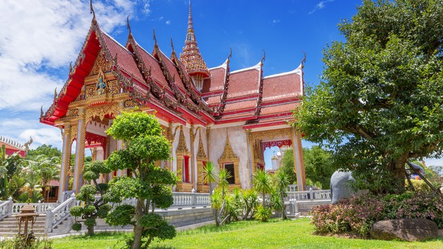 Bunter thailändischer Tempel mit rotem Dach und Garten