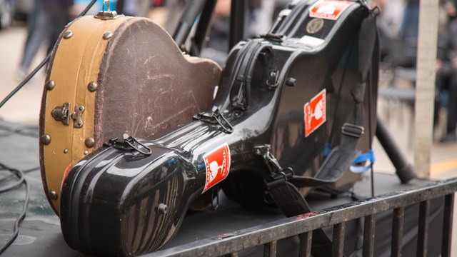 Zwei Gitarrenkoffer, einer schwarz mit Aufklebern, abgestellt im Freien