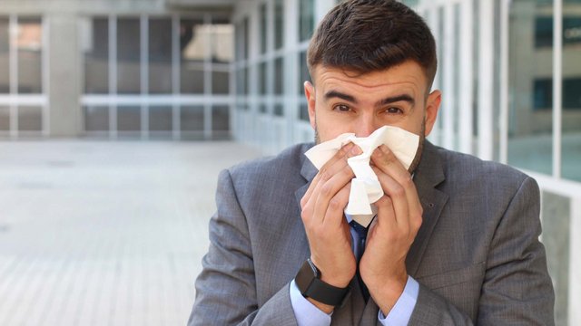 Mann mit Erkältung putzt sich die Nase