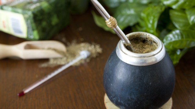 Traditionelles Mate-Gefäß mit Metallstrohhalm und Yerba-Tee auf einem Holztisch