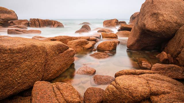 Rosa Granitfelsen am Meer in Ploumanac’h, Bretagne, mit Nebelstimmung
