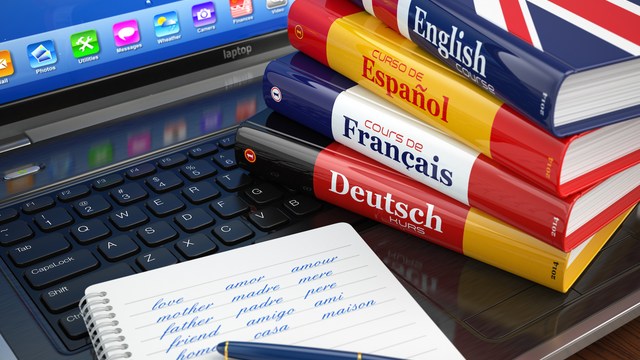 Sprachlern-Bücher Englisch, Spanisch, Französisch und Deutsch neben Laptop