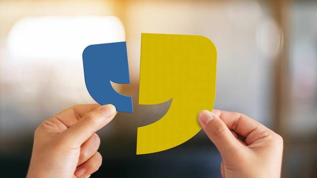 Zwei Hände halten blaue und gelbe Anführungszeichen-Symbole zusammen