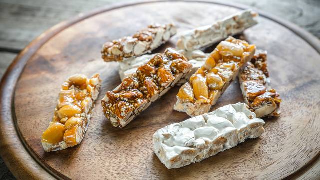 Spanische Süßigkeit Turrón, verschiedene Sorten mit Mandeln und Nüssen auf einem Holzbrett