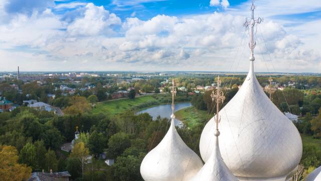 Blick über die russische Stadt Vologda mit Flusslandschaft im Hintergrund und den glänzenden Zwiebeltürmen einer orthodoxen Kirche im Vordergrund