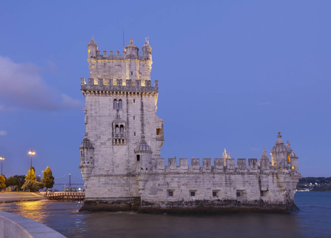 Historischer Turm Torre de Belém in Lissabon bei Dämmerung, mit blauem Himmel im Hintergrund