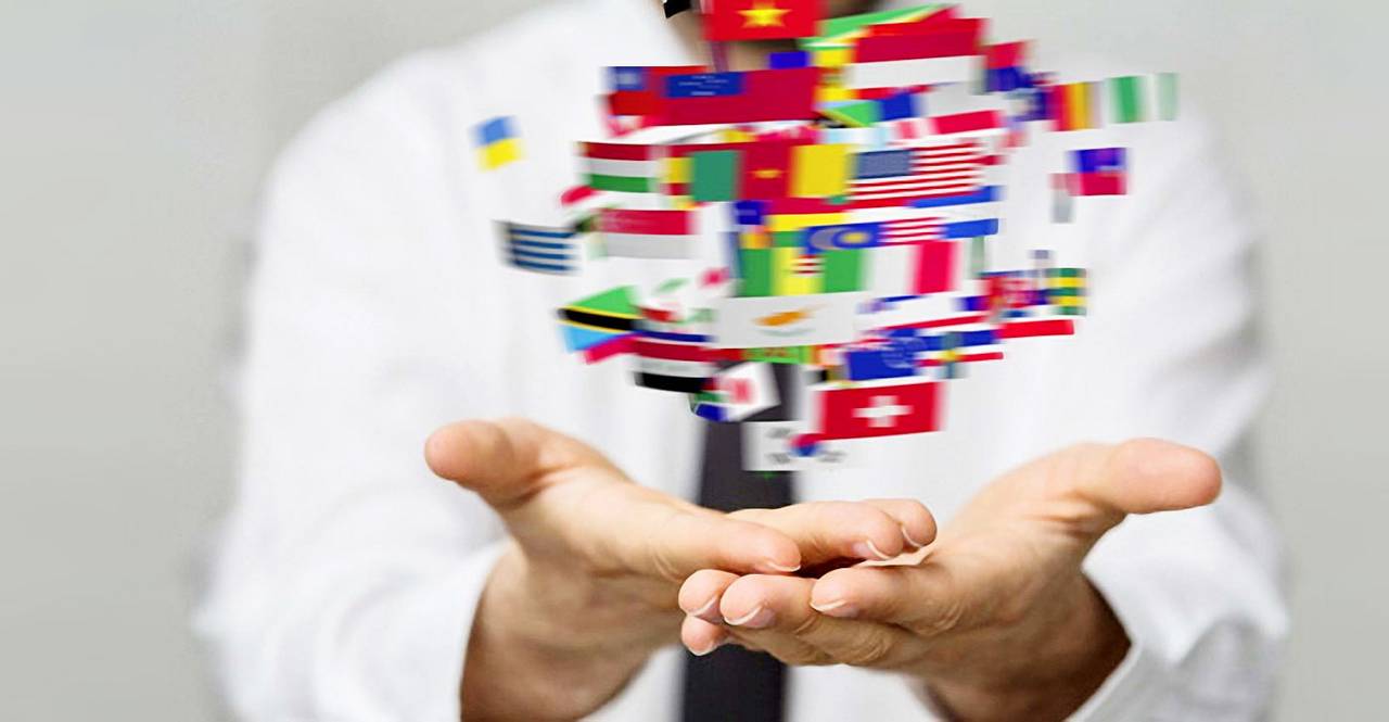 Viele bunte Länderflaggen schweben über geöffneten Händen