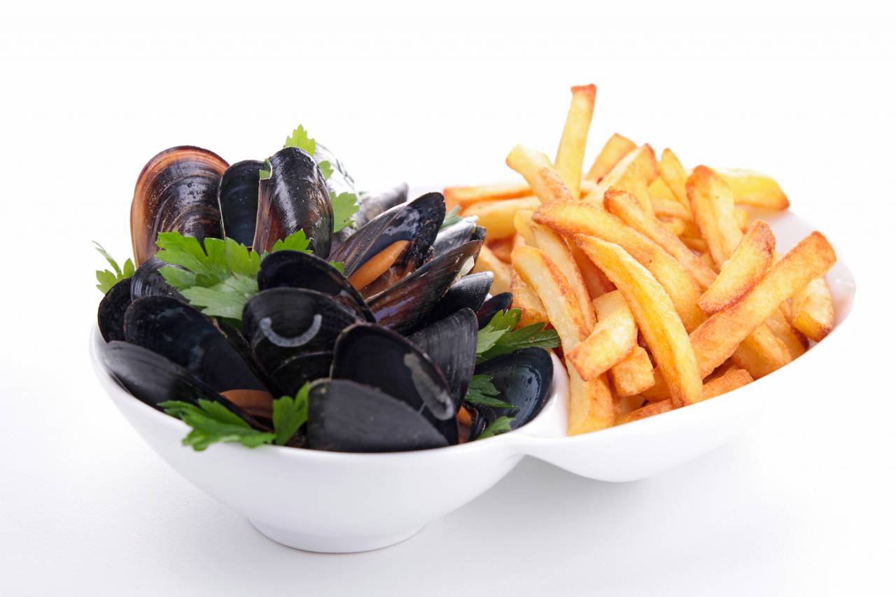 Klassisches Gericht – Muscheln mit knusprigen Pommes Frites, serviert in einer weißen Schale